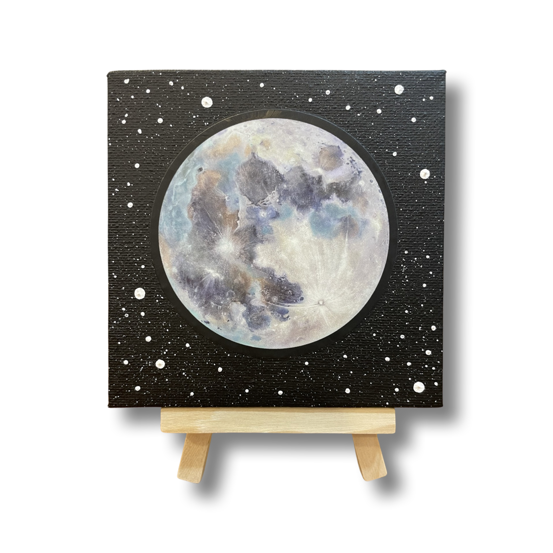 Four by four inch canvas on a natural wood stand. Painting depicts full moon against a black background with the impression of stars. The full moon is a vinyl sticker reproduction of an Elizabeth Schnura original painting, Magnolia's Moon, created in 2022.